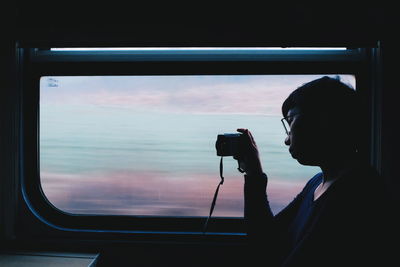 Woman photographing through window in train