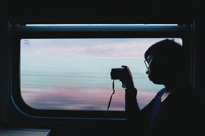 Portrait of woman photographing through window