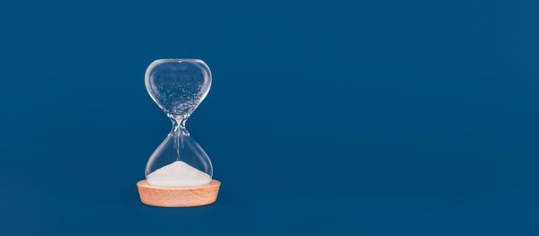 Close-up of hourglass against blue sky