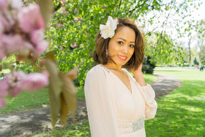 Portrait of smiling young woman standing against trees