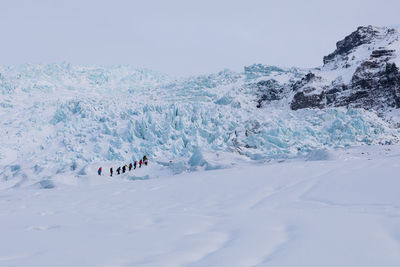 People on snowcapped mountain against sky