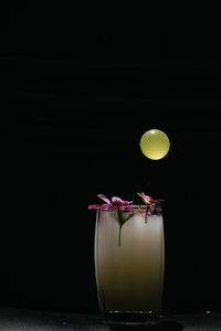 Close-up of yellow rose on glass table against black background