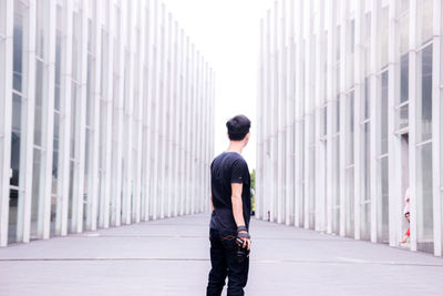 Rear view of man standing against wall in city