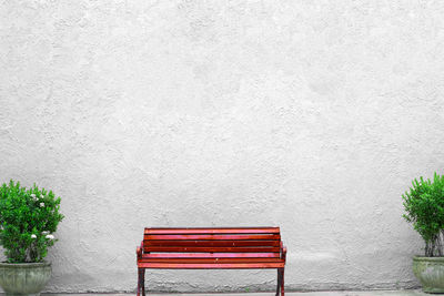 Empty red bench against white wall