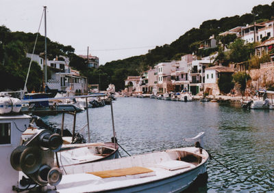 Boats moored in sea by town against sky
