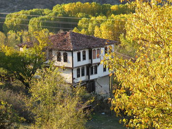 House by river amidst trees and buildings