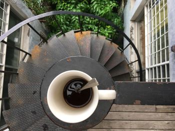 High angle view of coffee cup on railing over spiral staircase