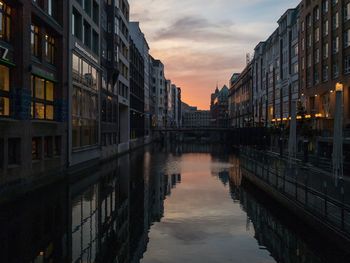 Canal amidst buildings against sky at sunset