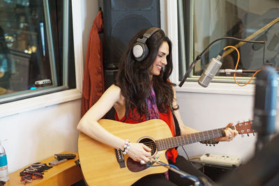 Young woman playing acoustic guitar at a recording studio