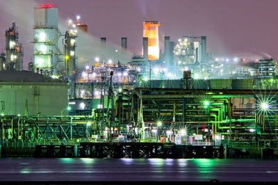 Illuminated factory against sky at night