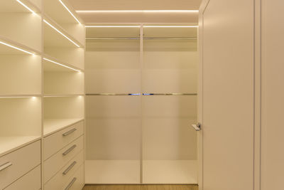 Spacious, empty, modern backlit wardrobe in light colours