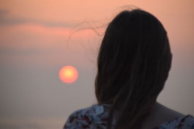 Close-up portrait of silhouette woman against orange sky