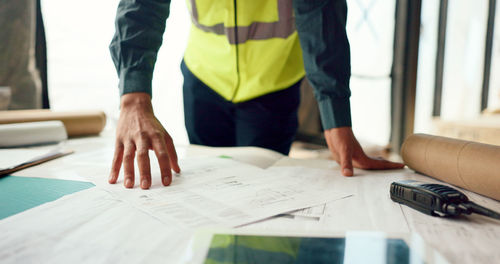 Hands of architect check blueprint at construction site for building.