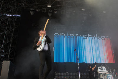 Full length of man holding umbrella while standing at music concert