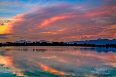 Scenic view of lake against dramatic sky during sunset