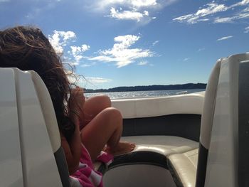 Woman sitting in boat against cloudy sky during sunny day