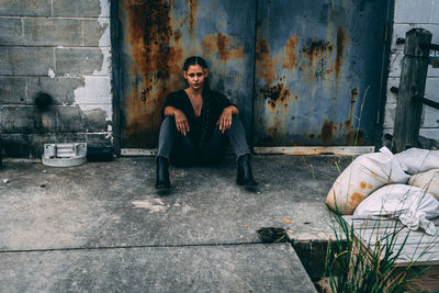 Portrait of young man sitting on wall of building