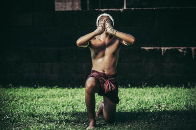 Full length of shirtless man standing in grass