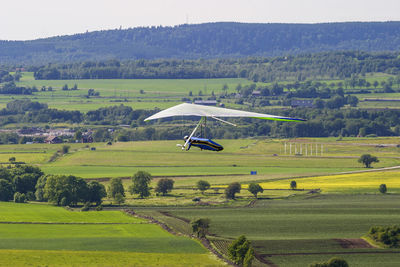 Hang glider flying over a rural landscape in the summer