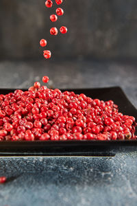 Pour red peppercorns on top of plate of pepper