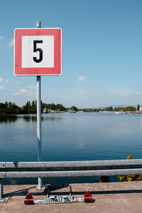 View of number on sign board against cloudy sky