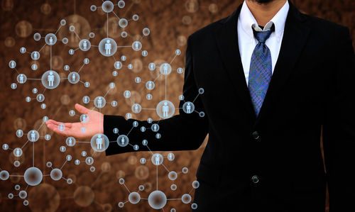 Midsection of businessman holding icons against defocused background