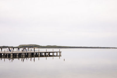 Wooden posts in lake against clear sky