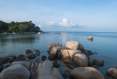 Rock formations on coast against cloudy sky