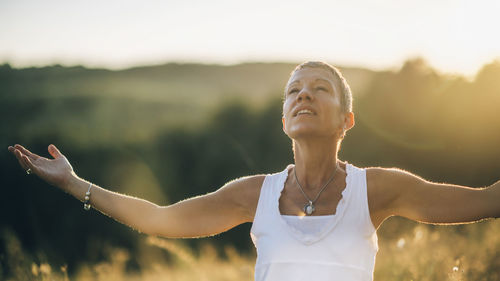 Woman with arms outstretched standing outdoors