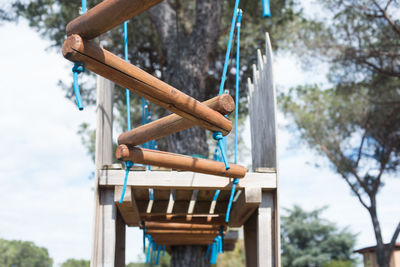 Low angle view of wooden suspension bridge against trees