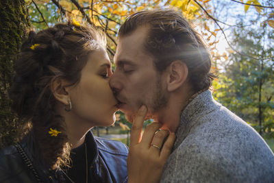 Portrait of young couple kissing against trees