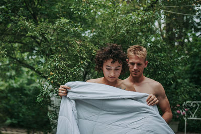 Portrait of couple standing against trees