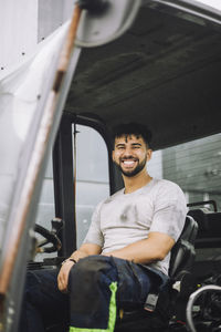 Happy young construction worker sitting in vehicle