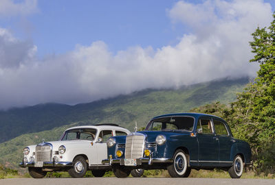 Vintage car on road by mountains against sky