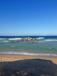 Scenic view of beach against clear blue sky