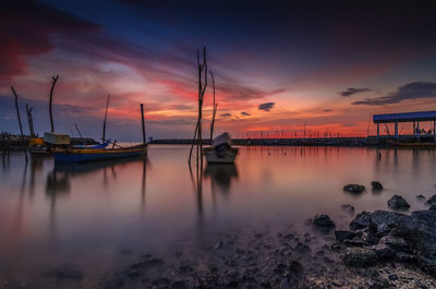 Boats moored at shore against sky during sunset