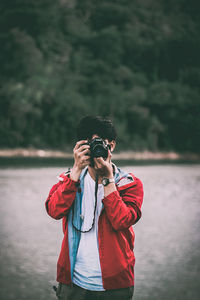 Man photographing while standing by lake