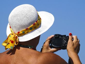 Rear view of woman photographing camera on beach