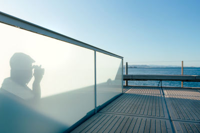 Man photographing sea against clear sky