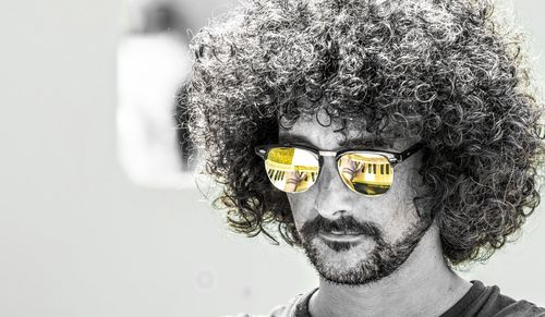 Portrait of man wearing sunglasses against gray background