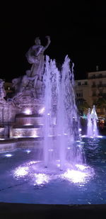 Water splashing in fountain at night