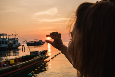 Woman photographing sea against sky during sunset