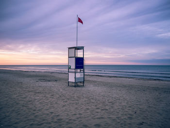 Lifeguard hut on beach against sky during sunset