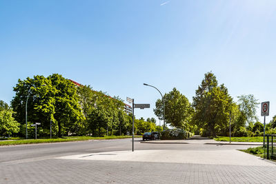 Road by trees in city against clear sky