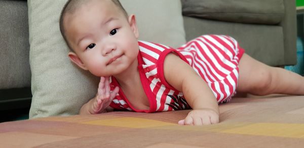 Portrait of cute baby girl lying on sofa at home