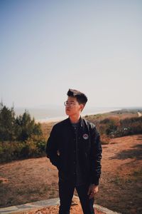 Portrait of young man standing on land against sky