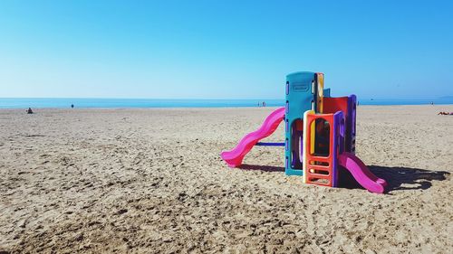 Deck chairs on beach against clear blue sky