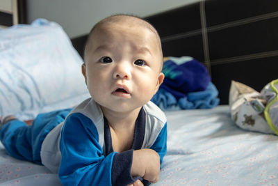 Portrait of cute baby lying on bed at home