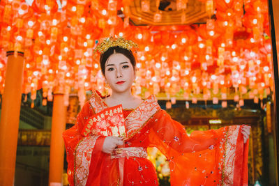 Portrait of young woman in traditional clothing standing at shrine