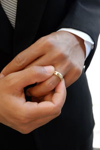 Midsection of groom wearing wedding ring